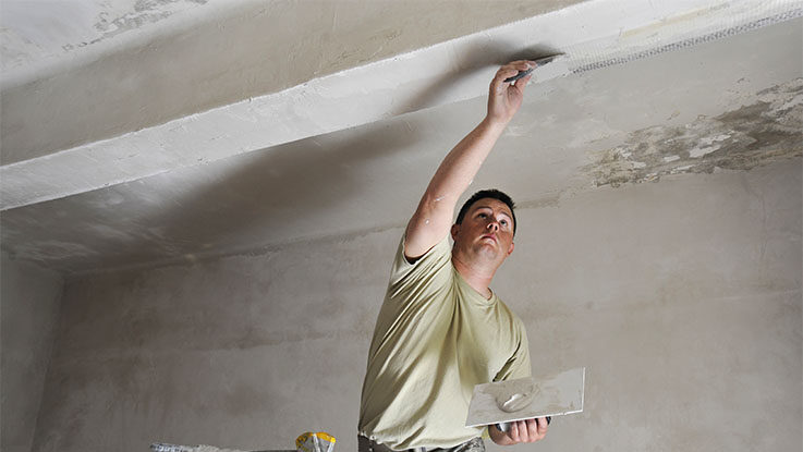 man applies plaster to ceiling